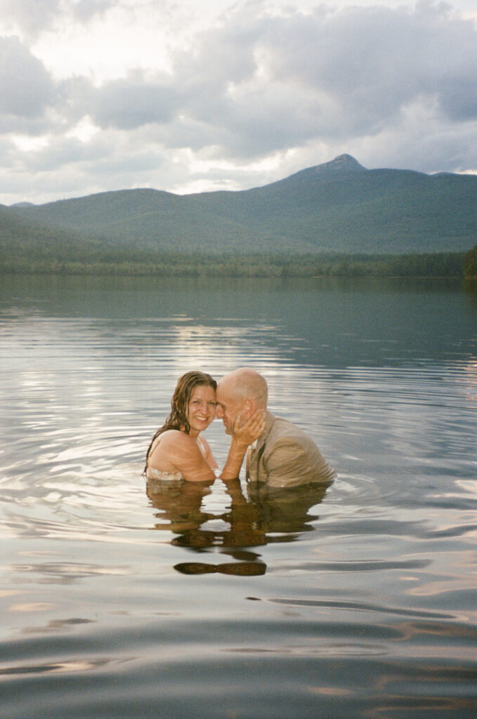 A couple swimming in the lake during their summer elopement in the White Mountains.