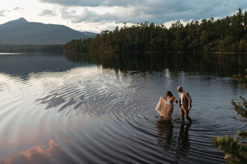 A couple walks in the lake at their Chocorua Lake elopement