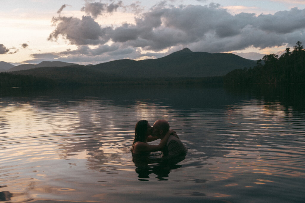A couple in Chocorua Lake for their Chocorua Lake elopement as the sunsets.