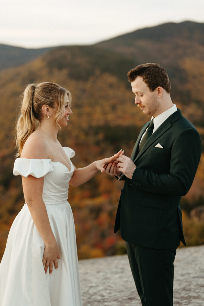 A couple exchanging rings on a mountain summit in the fall 