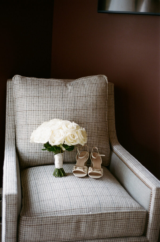 The brides shoes and bouquet on a tweed patterned chair. 