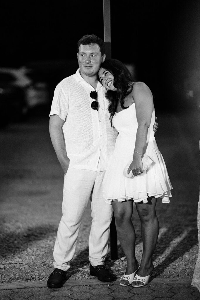 The couple snuggling in black and white while listening the father of the brides speech. 