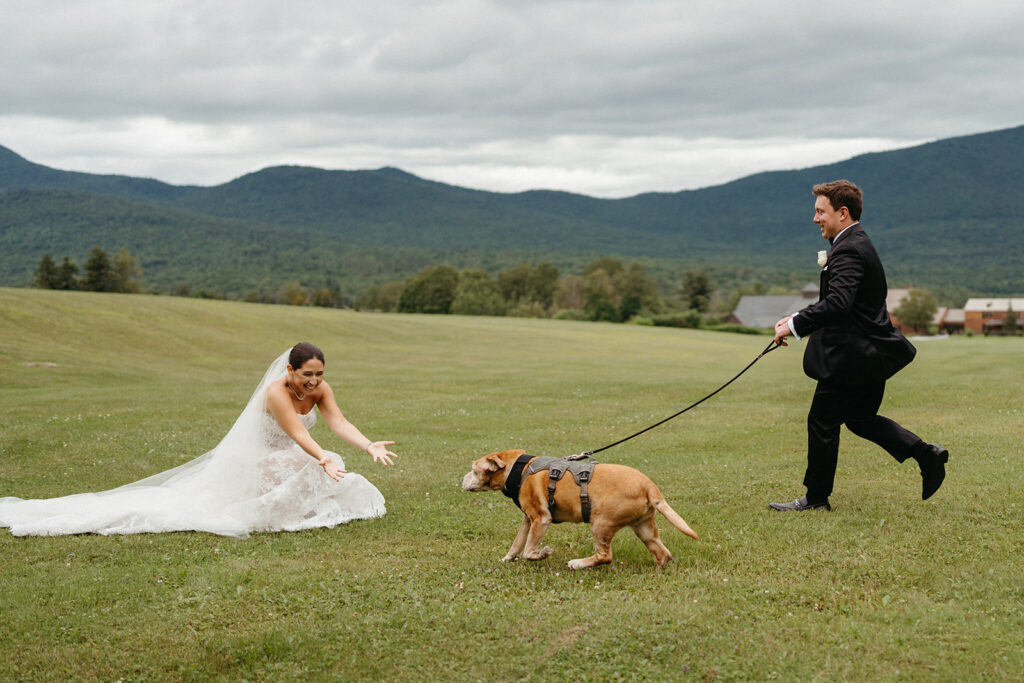The groom running to the bride with their dog at Mountain Top Resort in Vermont. 