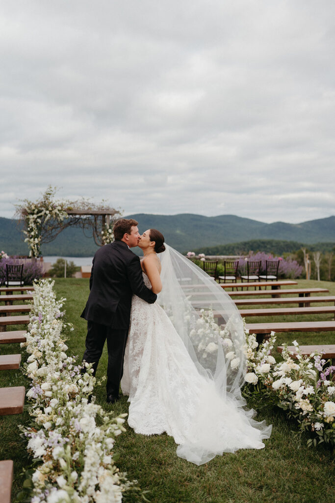 The newlyweds kissing in the middle of a flower lined aisle at The Knoll at Mountain Top Resort. 
