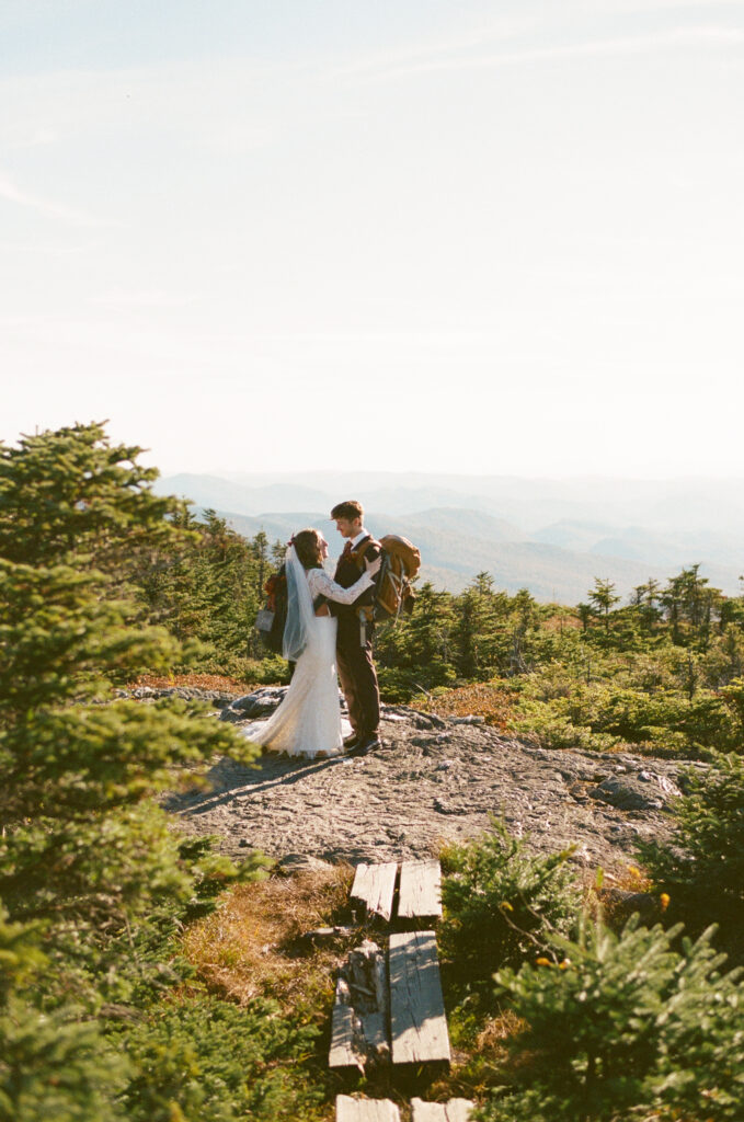 A couple with their backpacks on hiking the Mount Mansfield trail on their wedding day. 