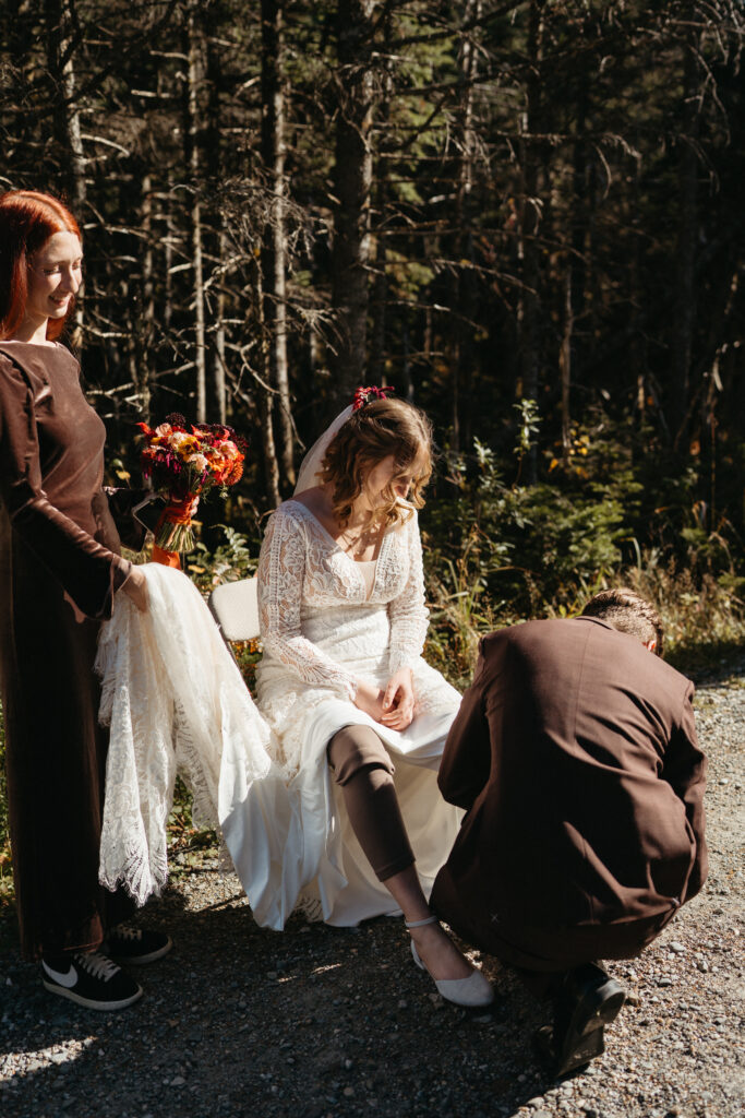 The groom helping the bride change out of her hiking boots into her flats for their ceremony on Vermont's Long Trail. 
